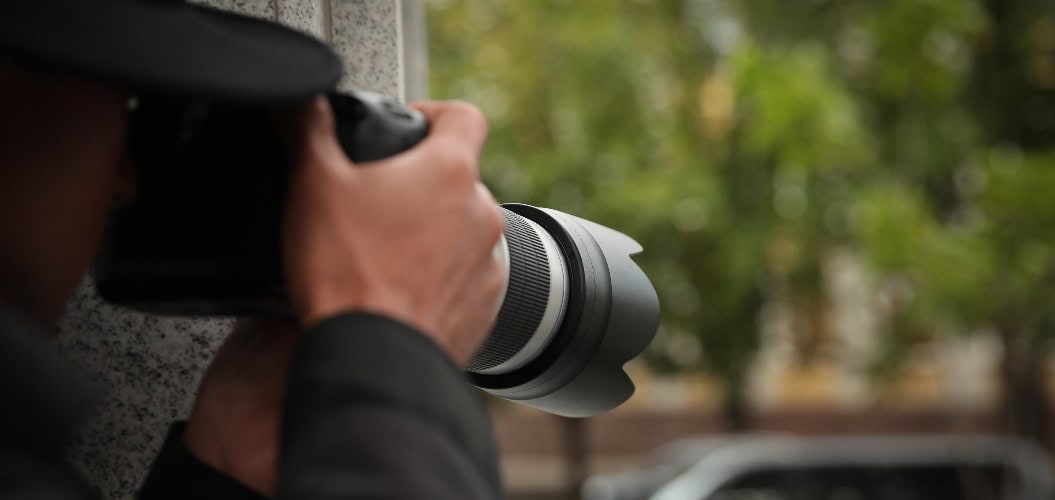 Privatdetektiv mit moderner Kamera spioniert auf der Straße, in der Nähe